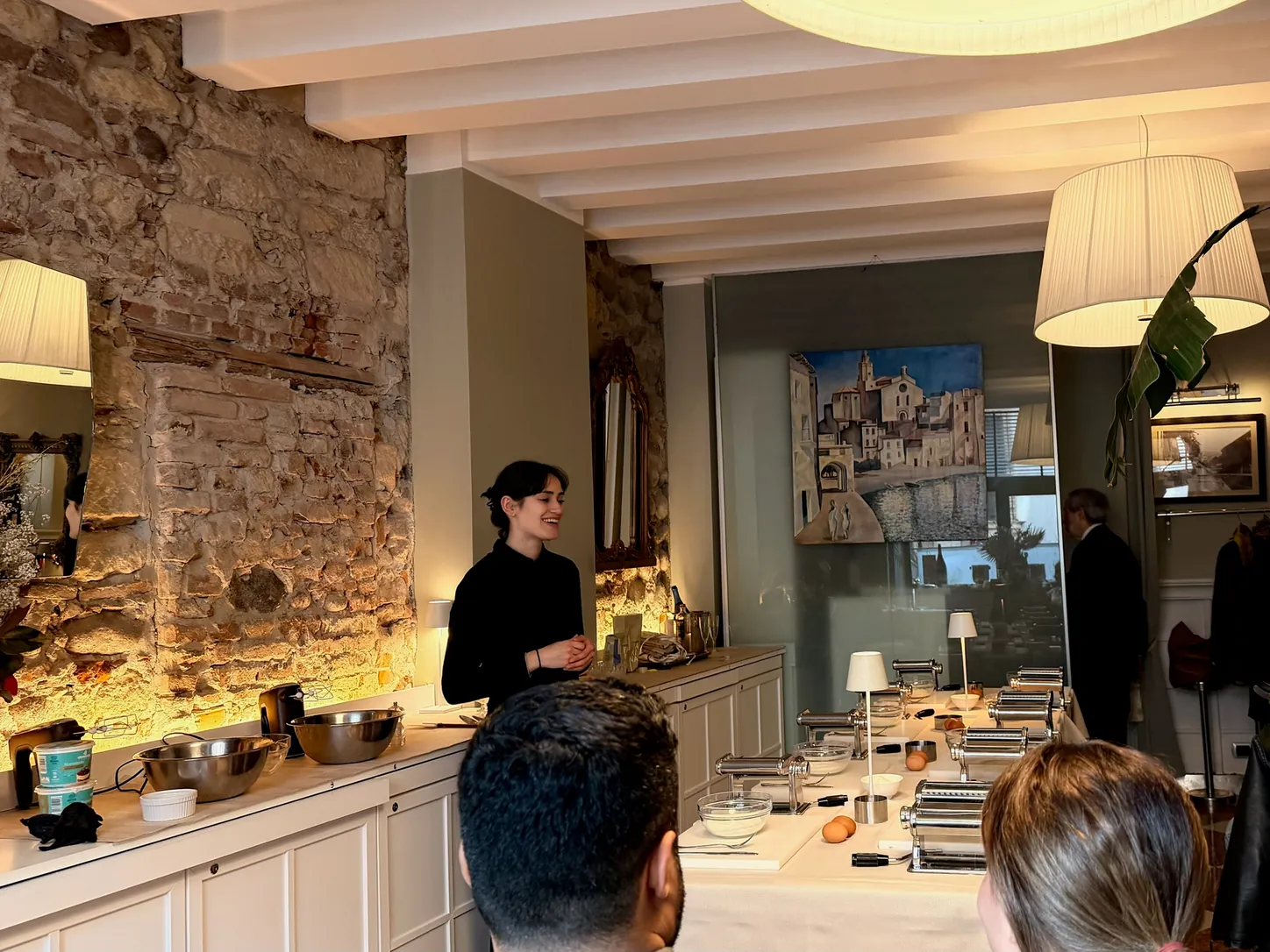A Cooking con Amore chef explains the class to guests gathered around the tables