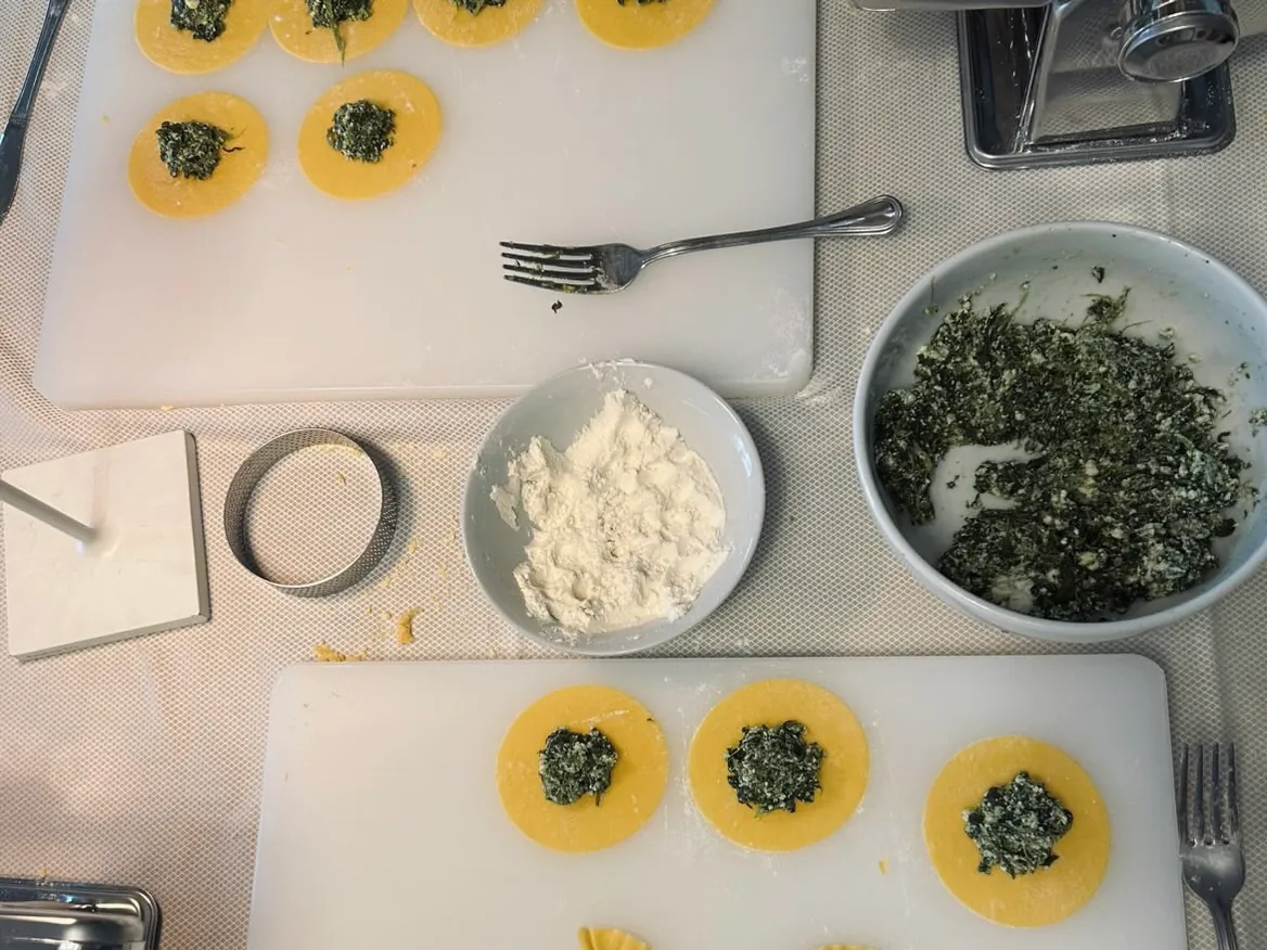 Ricotta, spinach filling and rounds of fresh pasta laid out for ravioli