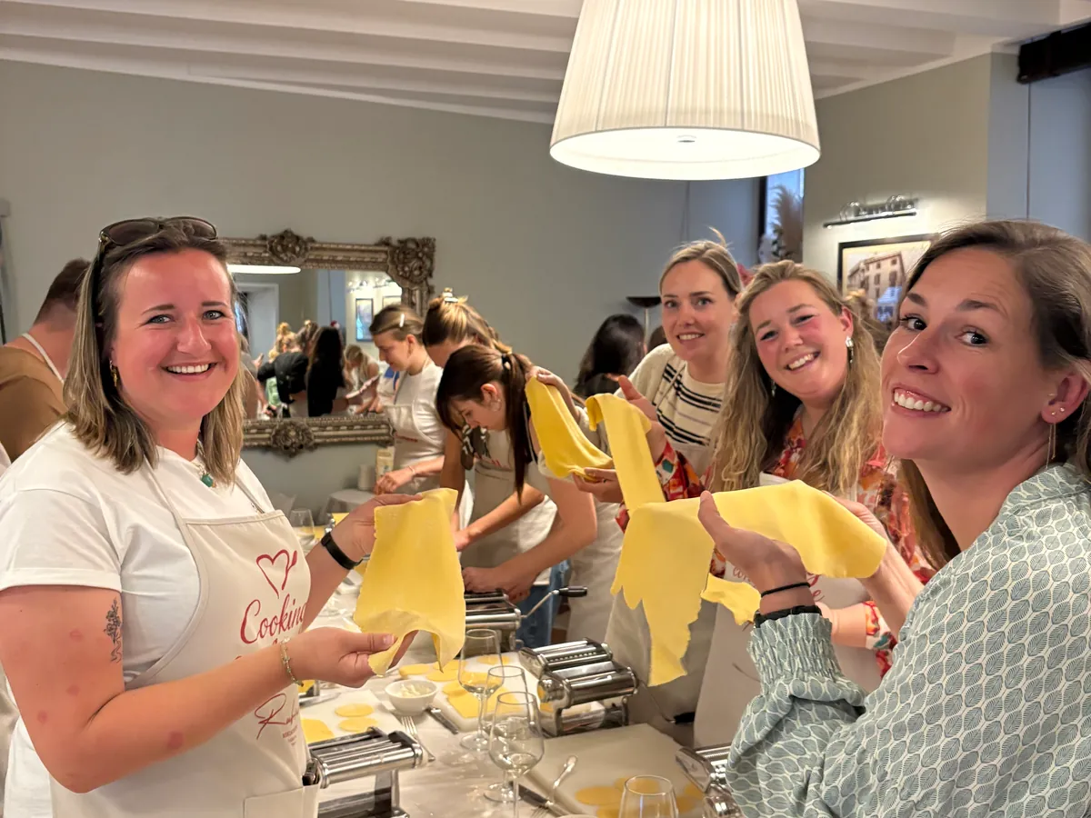 Smiling guests hold up the sheets of fresh pasta they have just rolled